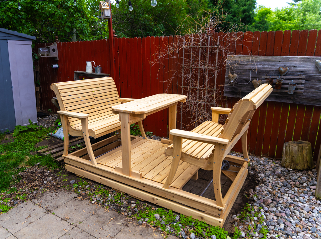 Handcrafted four-seater white cedar glider swing with facing curved contour benches and a built-in center table on a backyard patio by Matteout Woodworking.